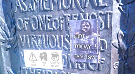 a plaque commemorating Colston with two antifascist sticers on it including 'not today, fascism' with a picture of Arya Stark